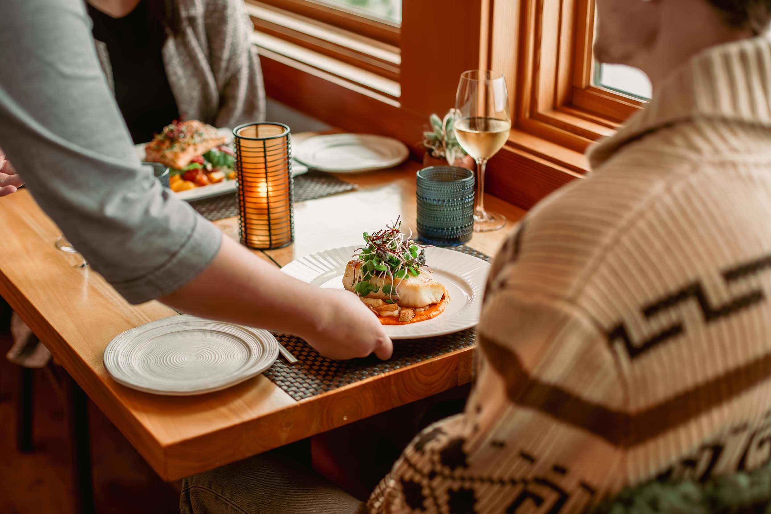 A couple eating at the Meridian restaurant and a server bringing them their dish