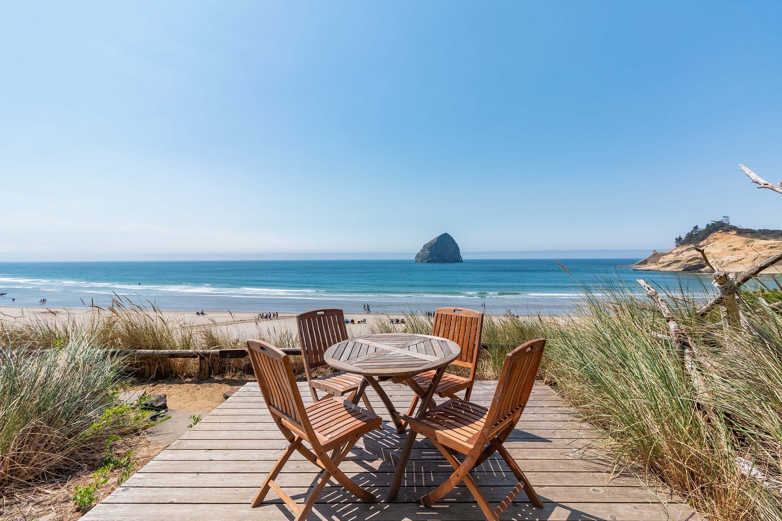 A patio with a circle table and 4 chairs outside a room at Headlands looking out to Haystack rock
