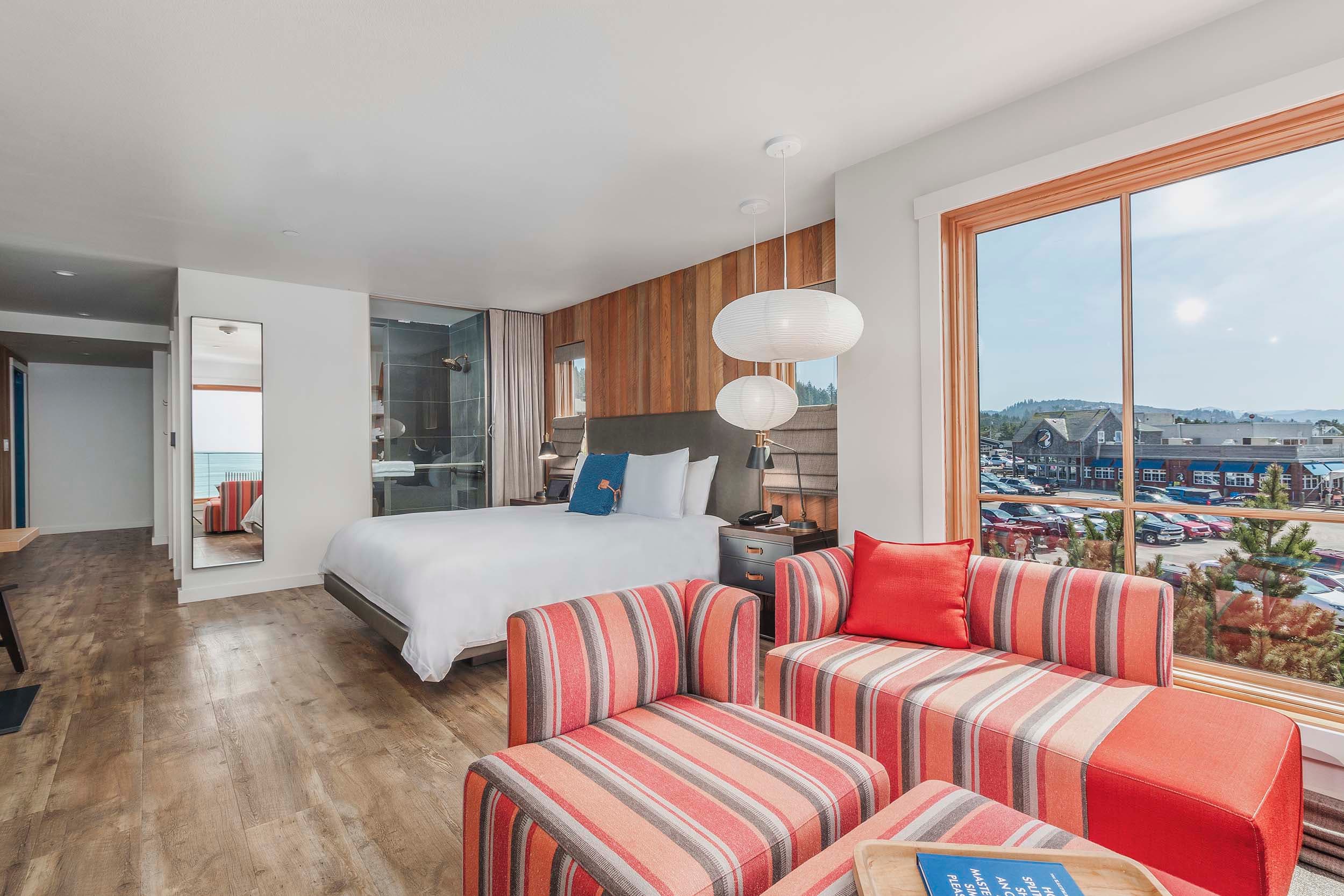 A lounge area and sleeping area with lots of windows looking onto the beach in a King Sunlight Accessible at Headlands