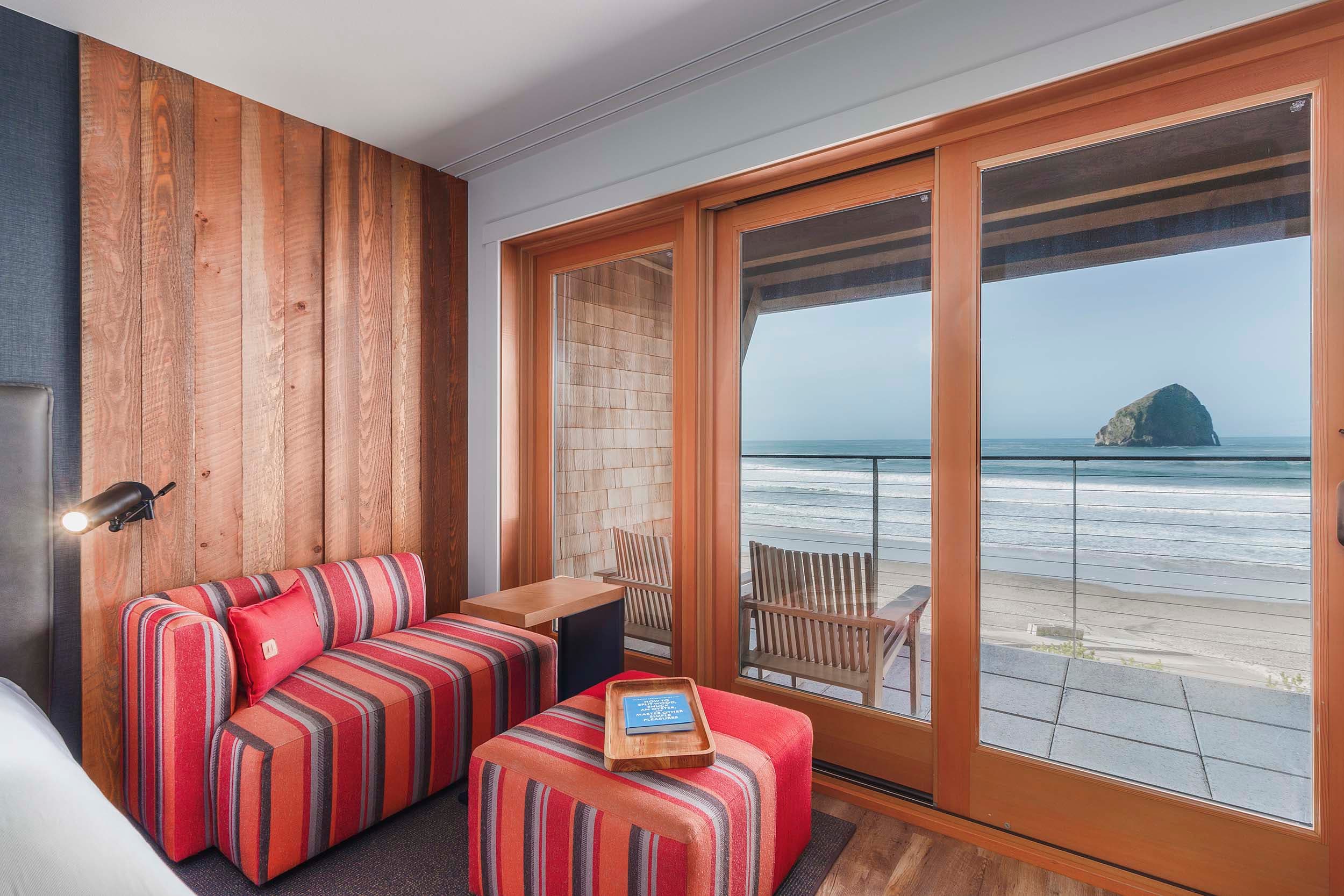 A corner lounge space with views of Haystack rock in a Two Queens Signature room at Headlands
