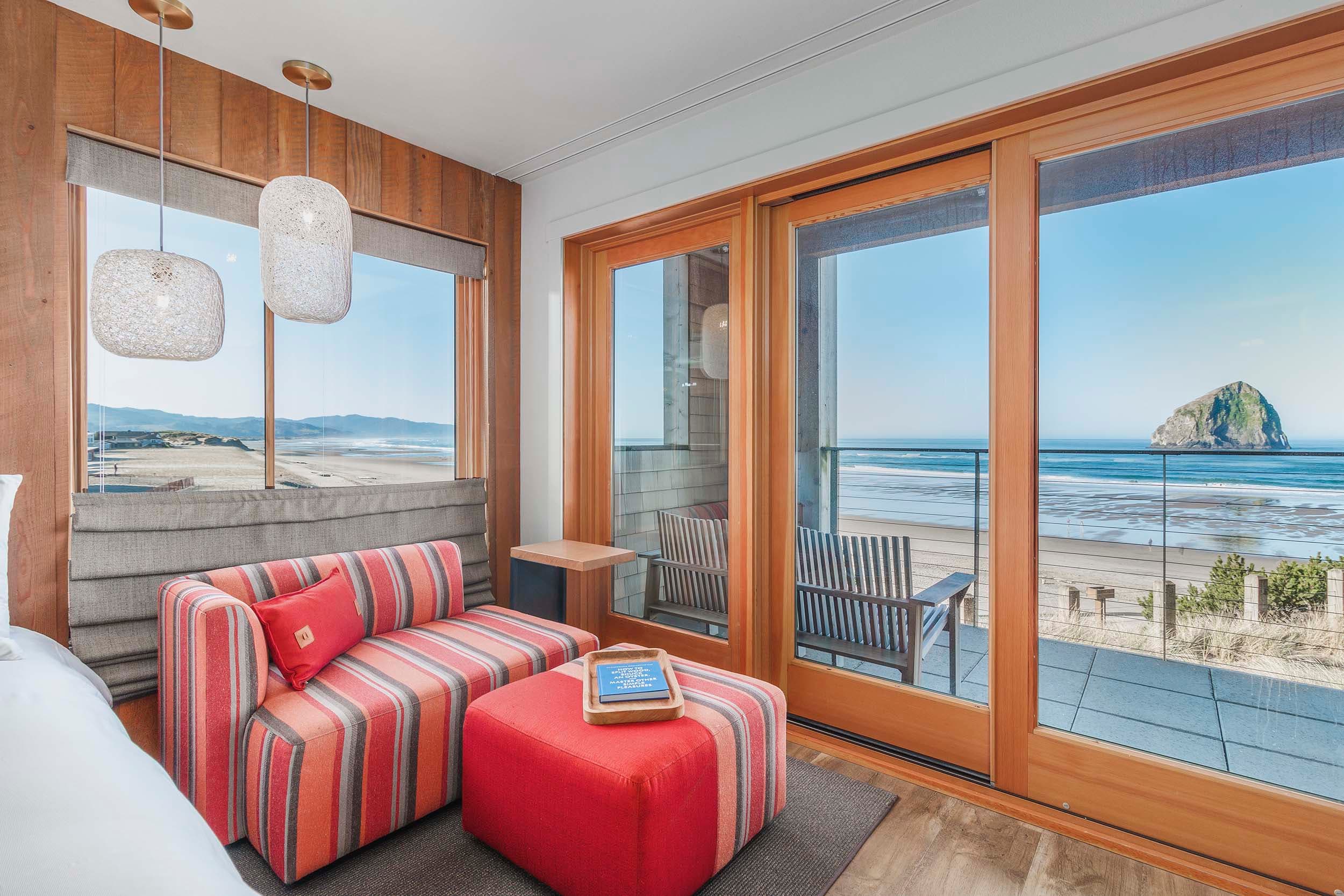 A lounge area with a view of haystack rock in a Two Queens Sunlight lodge at Headlands
