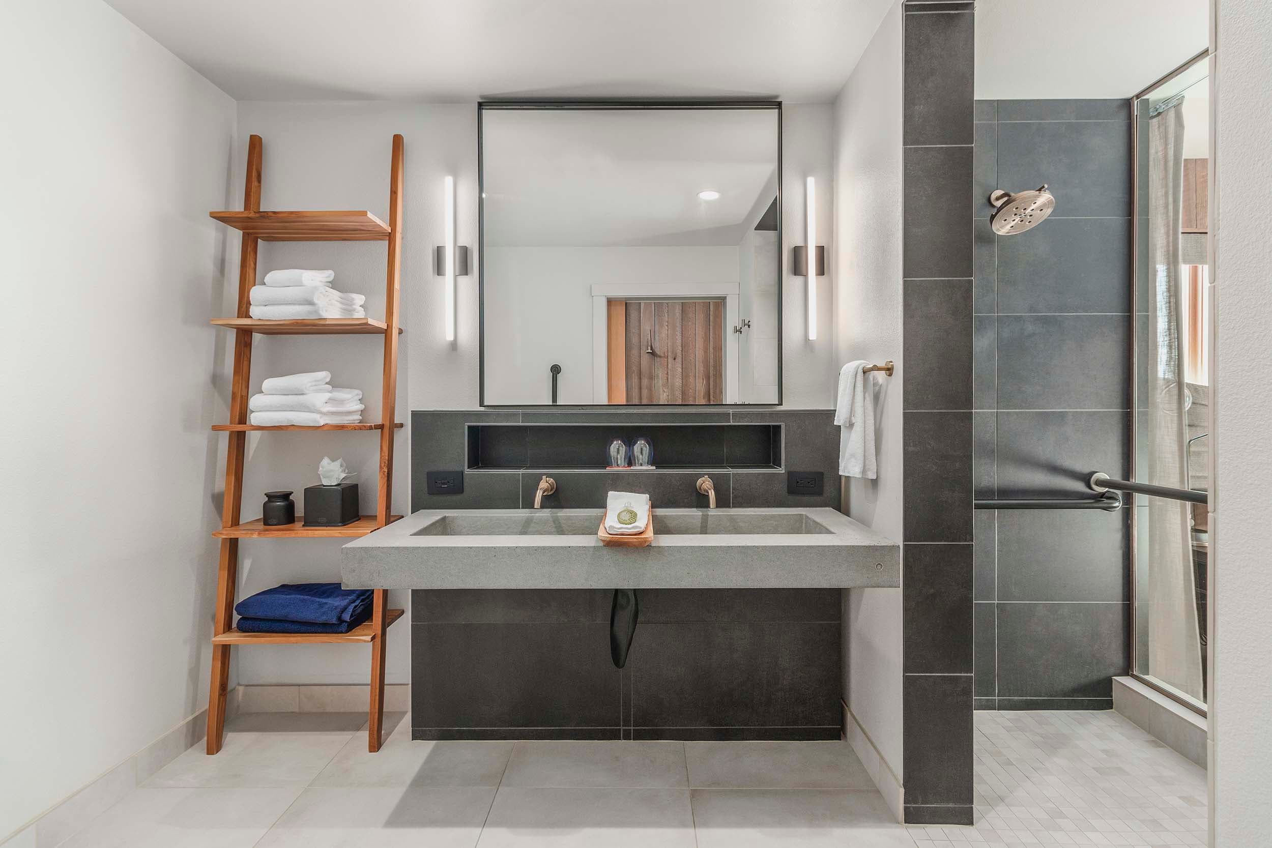 A modern washroom with dark tiles and bright lighting in a King Sunlight Accessible room at Headlands