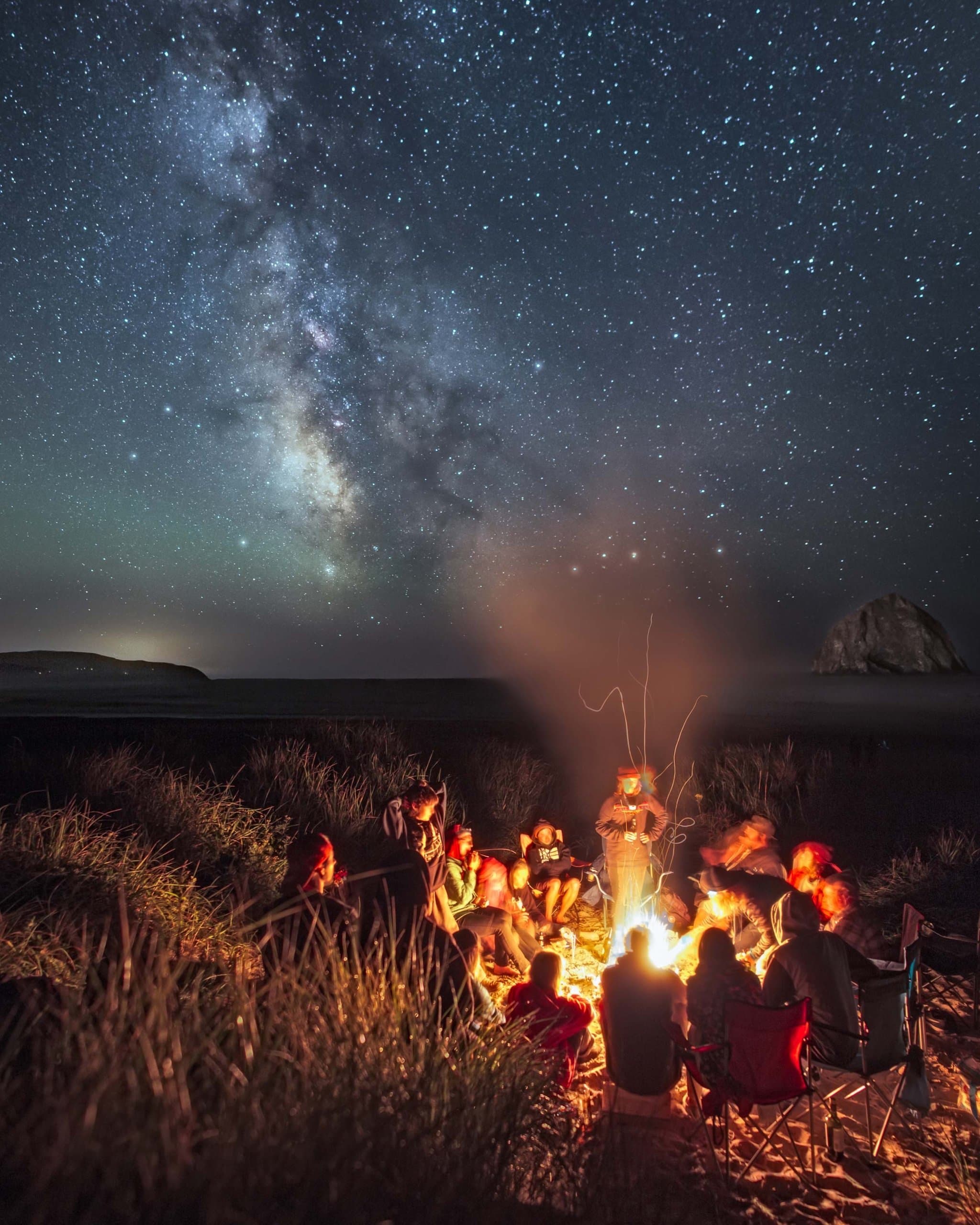 A bunch of people surrounding a fire during a star party at Cape Kiwanda