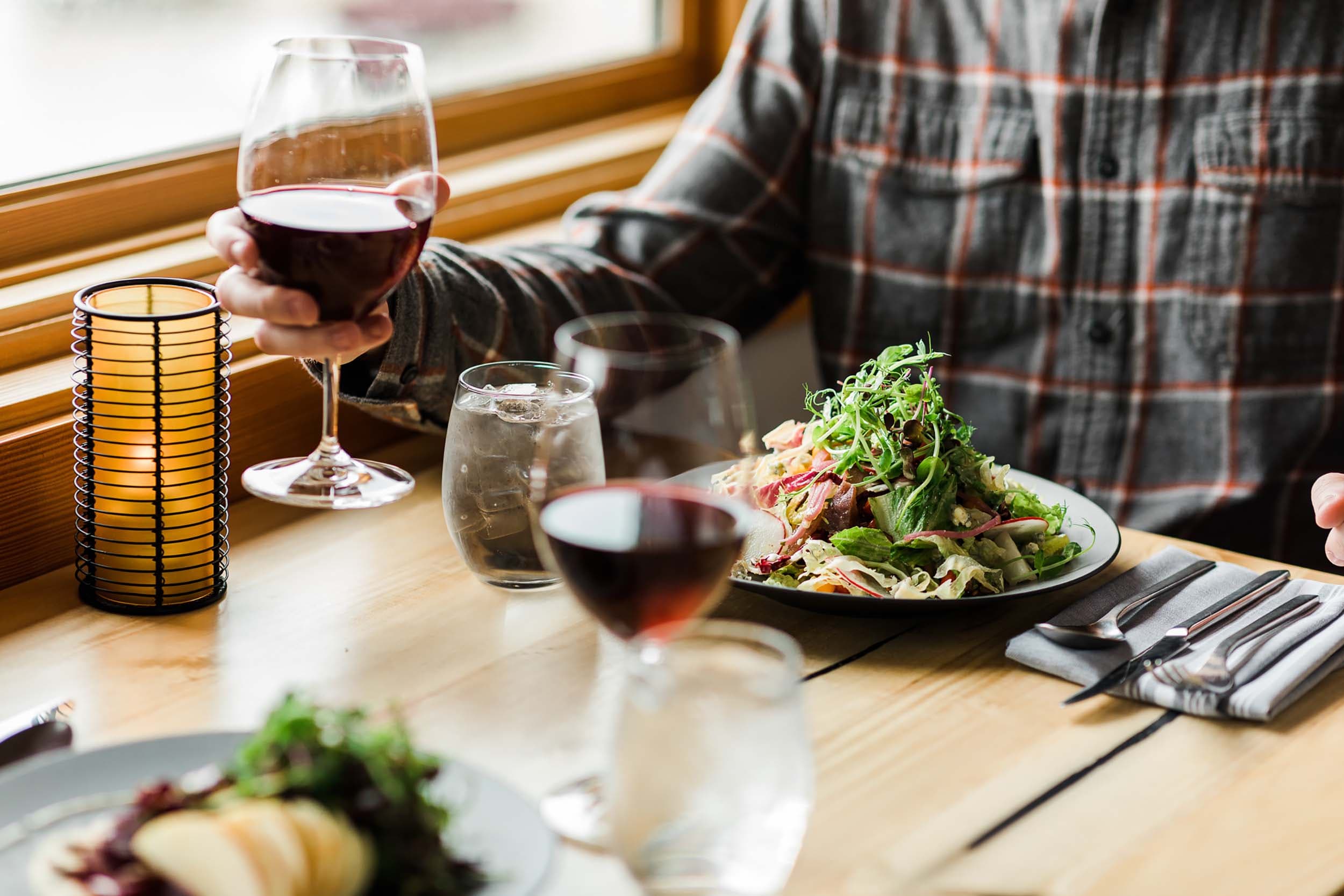 A man eating a salad and having a glass of read wine at Meridian restaurant near Headlands