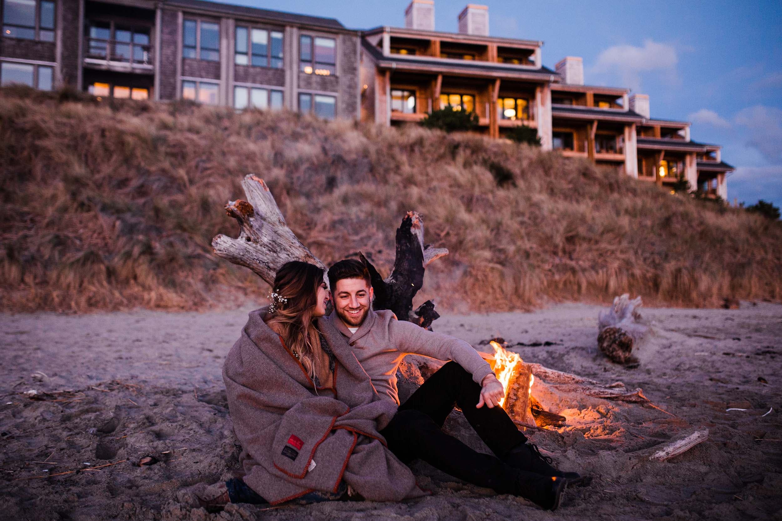 A couple embracing on the beach in front of a fire pit