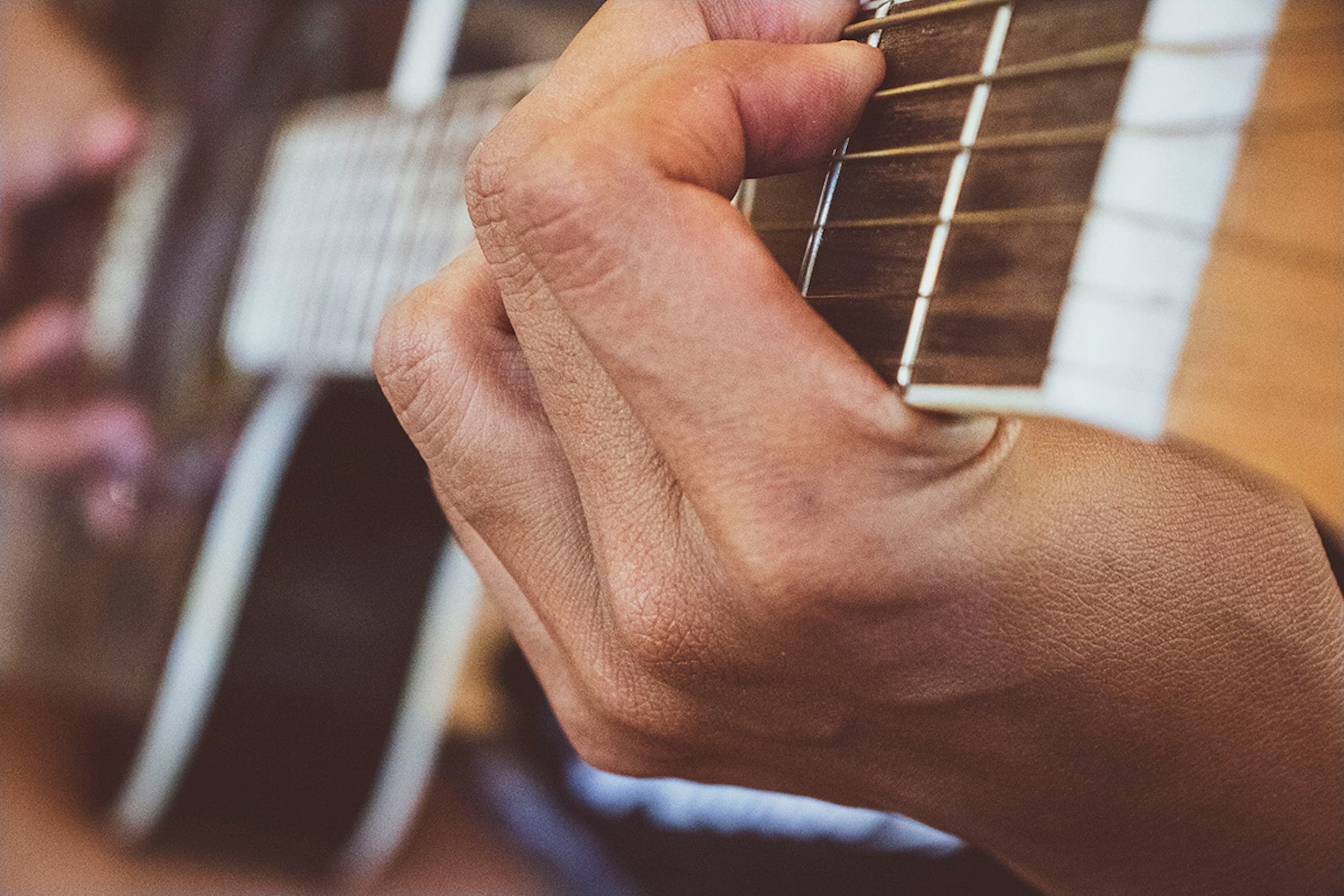 A close up of a hand playing guitar at Headlands Coastal Chords And Corks