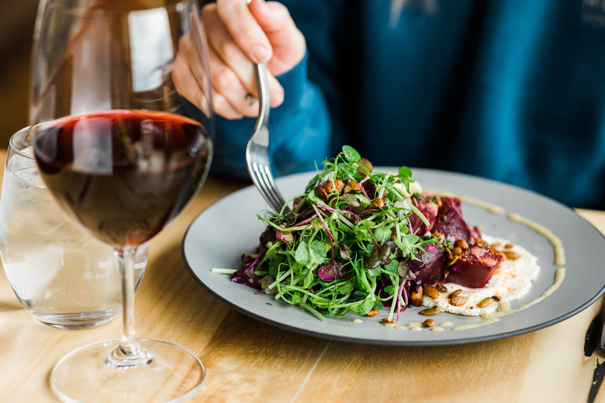 A beet salad with pea shoots, seeds, and a glass of red wine at Meridian Restaurant